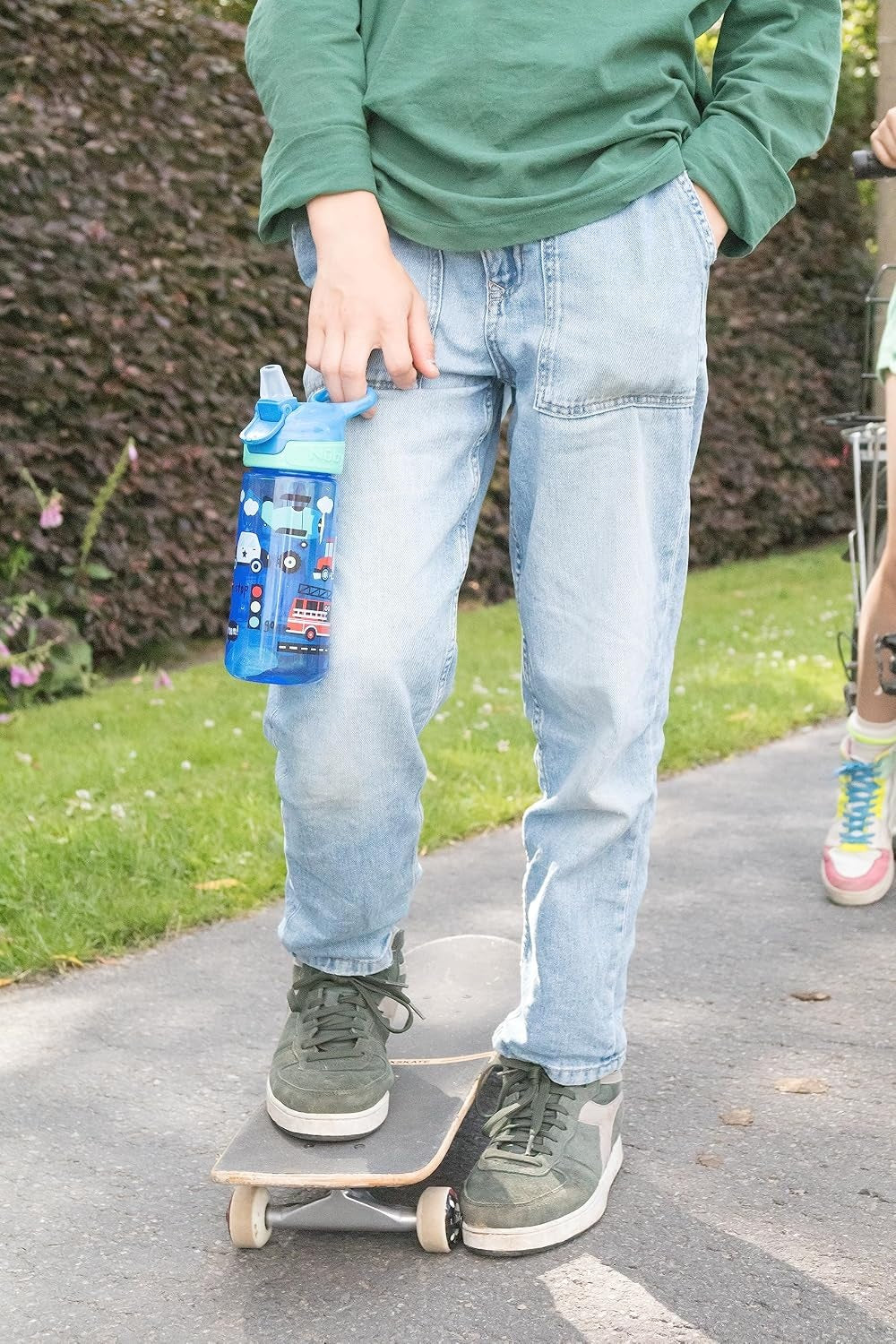 Nuby Flip it Cup – dziecko trzymające kubek podczas jazdy na hulajnodze